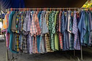 Numerous colorful checkered-patterned shirts. photo