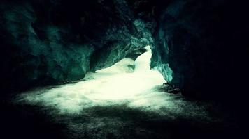 blue ice cave covered with snow and flooded with light
