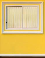 White frame window in yellow wall with curtain. photo