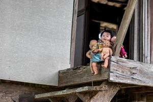 Many baby dolls sit on old wooden house balconies. photo