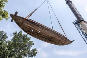 antiguos barcos de madera en descomposición están siendo movidos por grúas y cuerdas de alambre. foto