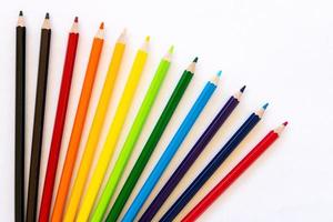 Many colorful pencil isolates spread on white paper. photo