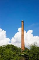 Old brick chimneys in a forest overgrown with sky clouds. photo