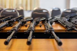 A close-up shot of rifle weapons lined up on a wooden table. photo