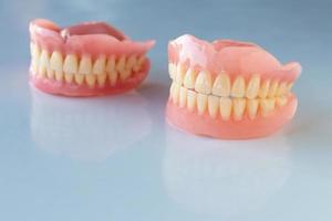 The dentures of the two elderly people were placed on a shiny white table. photo