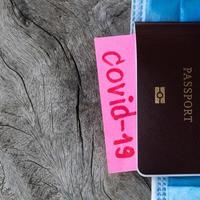 COVID-19 with passport and face mask on wooden floor. photo