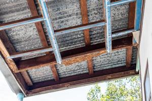 A decayed wood structure under the zinc roof of a house. photo
