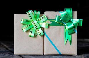 Two gift wrappers with a green bow on a black backdrop. photo