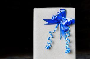 Gift wrap with blue bow on a black background. photo