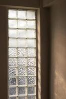 Glass brick wall with sunlight shining through the room. photo