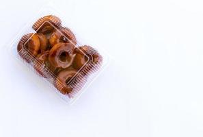 rosquillas fritas de tailandia, recubiertas de caramelo en una caja de plástico transparente sobre un fondo blanco. foto