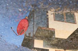 The water reflection of the red satellite dish against the building. photo