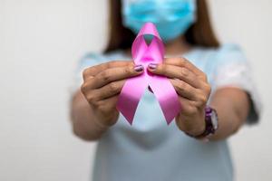 Close-hand woman wears a mask as a symbol against breast cancer. photo