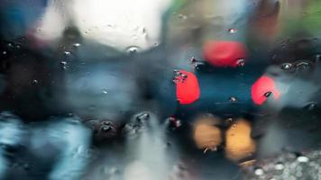 desenfoque de fondo abstracto del parabrisas de un camión mirando a través de muchas gotas de lluvia a la luz roja al final del camión, que estaba estacionado en la calle por la noche. foto