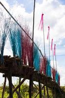 A low, close-up view of a bridge of eucalyptus logs decorated with brightly colored twigs. photo