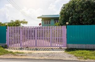 A large pink fence gate close to the house. photo