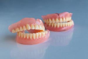 The dentures of the two elderly people were placed on a shiny white table. photo