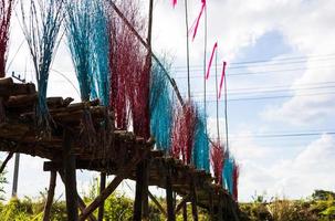 A low, close-up view of a bridge of eucalyptus logs decorated with brightly colored twigs. photo