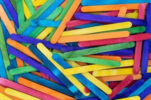 Popsicle sticks of various colors are stacked on top of each other. photo