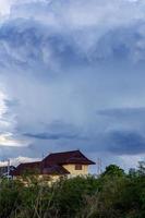 cielo nublado sobre una casa cerca del monte. foto