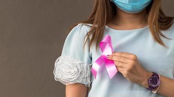 mujer de mano cercana usa una máscara como símbolo contra el cáncer de mama. foto
