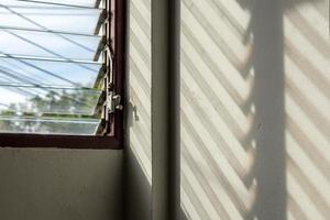 The sun shines through the louver windows into the concrete wall. photo