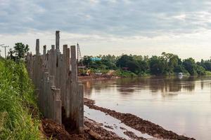 Many concrete columns form a long wall near the riverbank. photo