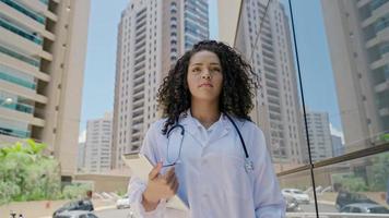 una joven doctora latina usa uniforme blanco, usando una tableta digital en el hospital