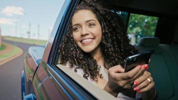 Beautiful Latin woman tourist traveling in a taxi and rewritten with your friends on your smartphone photo
