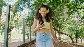 Latin woman using smartphone in the park. Brazilian girl. photo