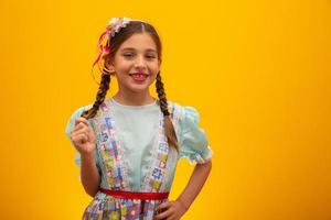 Child in typical clothes of famous Brazilian party called Festa Junina in celebration of Sao Joao. Beautiful girl on yellow background. photo