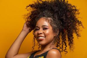Beauty portrait of african american woman with afro hairstyle and glamour makeup. Brazilian woman. Mixed race. Curly hair. Hair style. Yellow background. photo