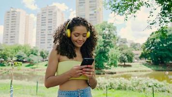 Latin woman using smartphone in the park. Brazilian girl. photo
