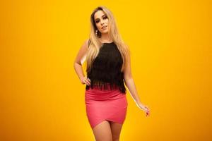 hermosa mujer rubia en el tema de la moda. joven mujer hermosa con camiseta de moda sobre fondo amarillo con sonrisa en la cara, expresión natural. riendo confiado. foto