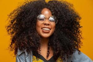 Beauty portrait of african american with glasses and afro hairstyle on a yellow background. Brazilian young woman. photo