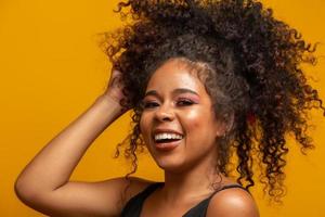 Beauty portrait of african american woman with afro hairstyle and glamour makeup. Brazilian woman. Mixed race. Curly hair. Hair style. Yellow background. photo