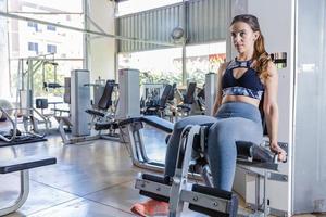 linda mujer joven durante un entrenamiento de piernas en un gimnasio foto