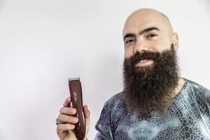 Bearded man will shave his beard with an electronic shaver photo