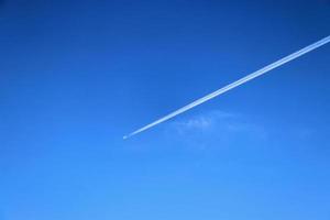 Estelas de condensación de aviones en el cielo azul entre algunas nubes foto