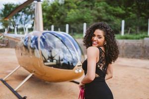 exitosa mujer latina joven inteligente y elegante cerca del helicóptero. concepto de estilo de vida de lujo foto