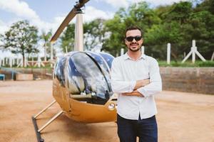 Pilot of private helicopter. Pilot near helicopter. Latin man. photo