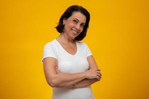 Attractive middle aged woman with folded arms on yellow background photo