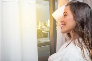 gente y concepto de esperanza - cerca de una mujer feliz abriendo cortinas de ventana foto