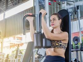 Girl training pectoral in gym apparatus photo