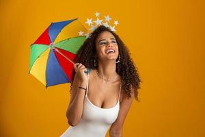 mujer joven de pelo rizado celebrando la fiesta del carnaval brasileño con paraguas frevo en amarillo. foto