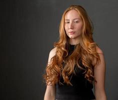 Portrait of beautiful cheerful redhead girl smiling laughing looking at camera over black background. photo