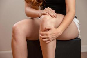Bone pain or knees around the knee. The girl's hand is holding the knee area. Redhead woman. photo