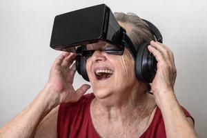 Happy grandmother use modern VR goggle glass on white background. New trends and technology concept and funny active elderly. photo