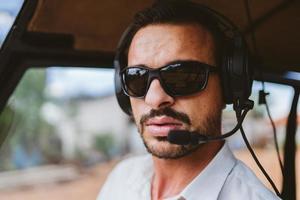Pilot with headset initiating controls in private helicopter. Helicopter pilot sitting in the cockpit. Latin man. photo