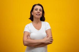 Attractive middle aged woman with folded arms on yellow background photo